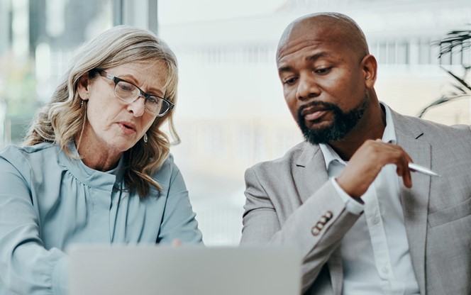Businessman And Businesswoman Using A Laptop Together In A Modern Office